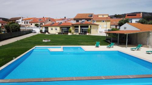 a large blue swimming pool in a yard with houses at Casas nas Hortas in Erada