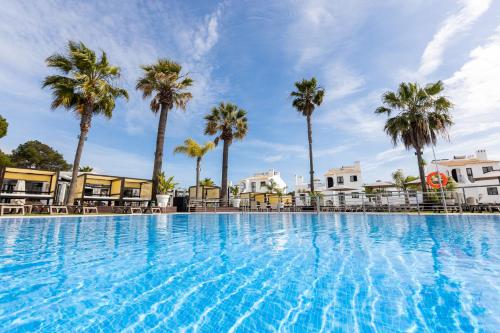 a large swimming pool with palm trees in the background at Apartamentos Honorio - Pool and Garden in Vilamoura