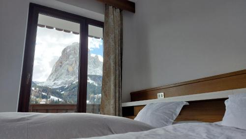 a bedroom with a window with a mountain view at Pension Dolomieu in Santa Cristina in Val Gardena