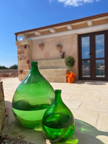 two green glass vases sitting in front of a house at I Trulli di Giorgia in Torre Suda