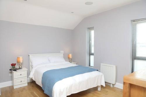 a white bedroom with a bed and two windows at Luxury Three Bedroom Apartment Foxford County Mayo in Foxford