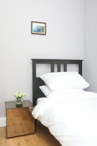 a bedroom with a bed with white pillows and a table at Foxford penthouse in Foxford