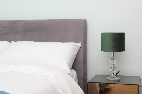 a bed with a green lamp on a side table at Foxford penthouse in Foxford