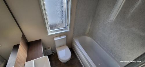 een kleine badkamer met een toilet en een raam bij 13 The Meadows New Beach Holiday Park in Kent