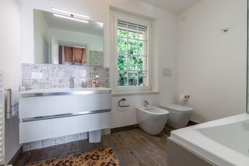 Baño blanco con lavabo y aseo en Italian Experience-Alloro Holiday Apartment, en Castello Ripalta