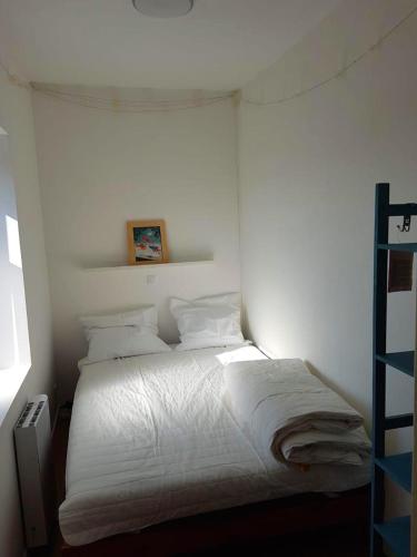 une chambre blanche avec un lit avec des draps et des oreillers blancs dans l'établissement le bien être, à Berck-sur-Mer