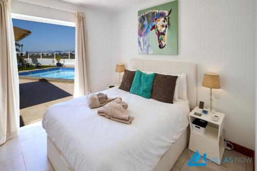 Schlafzimmer mit einem Bett und Poolblick in der Unterkunft Casa Nostra - LH195 By Villas Now Ltd in Playa Blanca