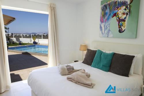Schlafzimmer mit einem Bett und Poolblick in der Unterkunft Casa Nostra - LH195 By Villas Now Ltd in Playa Blanca