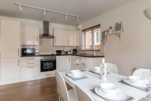 a kitchen with white cabinets and a white table and chairs at Bright, Modern, Fully Furnished Apartment - 2 FREE PARKING Spaces - 8 min LGW Airport in Crawley