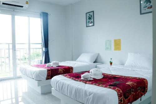 três camas num quarto com paredes brancas e janelas em โรงเเรมวังสะพุงอินวิว em Loei