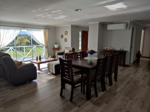 a dining room and living room with a table and chairs at Casa de campo in Curacautín