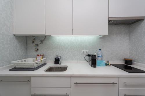 a kitchen counter with a sink and white cabinets at BeGuest Benfica Modern Flat in Lisbon