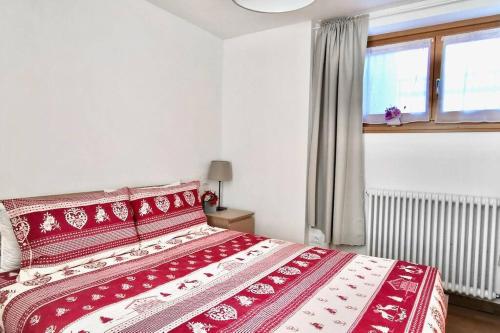 1 cama roja y blanca en un dormitorio con ventana en CASA APRICA 6 by Design Studio, en Aprica