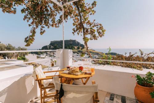 a table on a balcony with a view of the ocean at ARTE LINDOS SUITES in Líndos