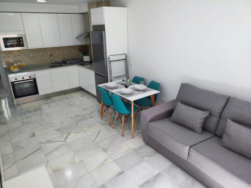 ein Wohnzimmer mit einem Sofa und einem Tisch mit Stühlen in der Unterkunft Garu Apartamentos in Fuengirola