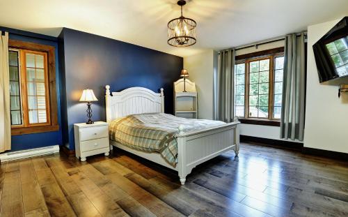 a bedroom with a white bed and a blue wall at Chalets Alpins - 16 Chemin des Skieurs in Stoneham