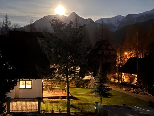 a view of a house with a tree and mountains at Domek Skała in Kościelisko