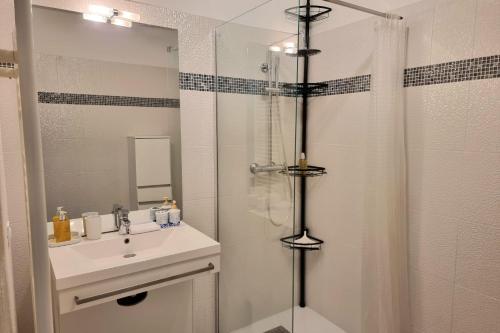 une salle de bain blanche avec une douche et un lavabo dans l'établissement Chez Lou et Dan 4P apartment with balcony elevator and secure parking, à Honfleur