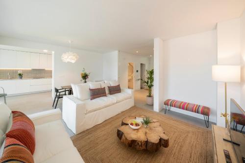 een woonkamer met een witte bank en een tafel bij CASA DO MIRADOURO 6 by Heart of Funchal in Funchal