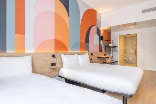 two beds in a room with a colorful wall at B&B HOTEL Mechelen in Mechelen