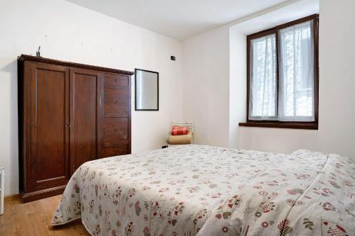 1 dormitorio con 1 cama y armario de madera en Appartamento nel cuore di Tenno, en Tenno