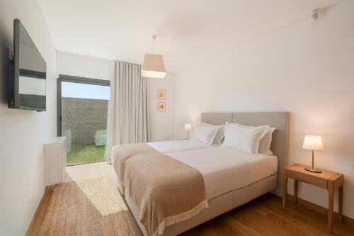 um quarto branco com uma cama e uma janela em CASA DO MIRADOURO 5 by Heart of Funchal em Funchal