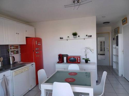a kitchen with a table and a red refrigerator at Plain-pied, terrasse, piscine, pleine vue mer, plage à 6' à pied, parking, wifi in Fleury