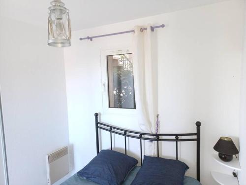 a bed with blue pillows in a room with a window at Plain-pied, terrasse, piscine, pleine vue mer, plage à 6' à pied, parking, wifi in Fleury