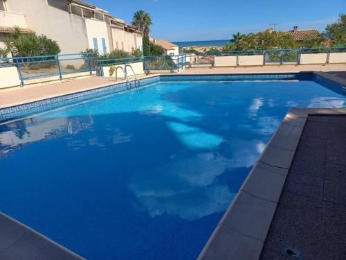 a swimming pool with blue water in front of a building at Plain-pied, terrasse, piscine, pleine vue mer, plage à 6' à pied, parking, wifi in Fleury