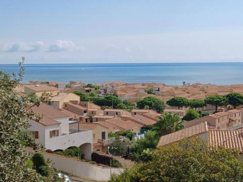a town with houses and the ocean in the background at Plain-pied, terrasse, piscine, pleine vue mer, plage à 6' à pied, parking, wifi in Fleury