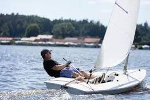 a man sitting on a sail boat in the water at Bungalow direkt am See, mit eigenem Boot in Roding