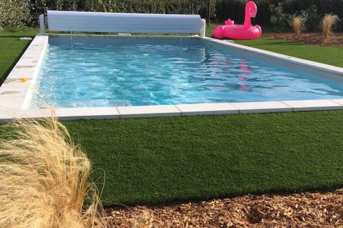 - une piscine avec un jouet flamant dans l'herbe dans l'établissement La remise d'Angèle, à Prigonrieux