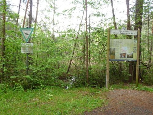 a sign in the woods next to a trail at Bungalow direkt am See, mit eigenem Boot in Roding