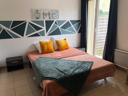 サンティレール・ド・リエにあるLes Villas des Pinsのベッドルーム1室(オレンジと黄色の枕を使用したベッド2台付)
