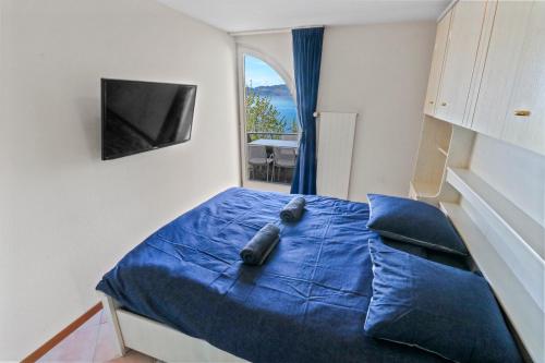 a bedroom with a blue bed with a window at Splendide logement avec vue plongeante sur le lac in Saint-Gingolph