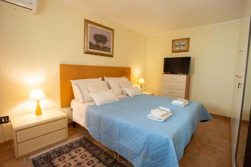 1 dormitorio con 1 cama azul y TV en Appartamento in Casa Olea, en SantʼAndrea