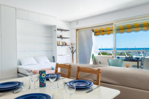 une salle à manger avec une table, des chaises et un canapé dans l'établissement Large studio with a breathtaking view of the sea, à Villeneuve-Loubet