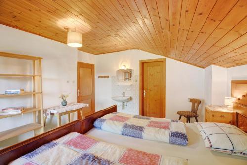 a bedroom with two beds and a wooden ceiling at Pitschlhof Apt Lärche in Aldino