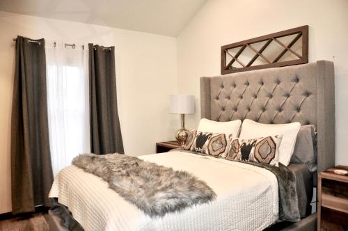 a bedroom with a bed with a gray headboard at Modern Luxury Bungalow steps from DT Activities in Rapid City