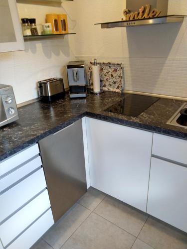 a kitchen with white cabinets and a black counter top at Ferienwohnung am Wäldchen in Kurort Gohrisch