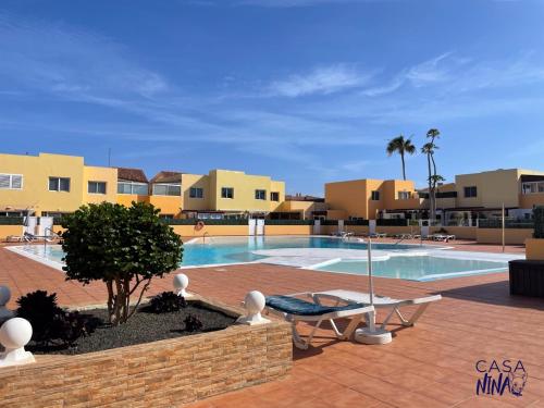a swimming pool in the middle of a resort at B-Rent Los Delfines Casa Nina in Corralejo