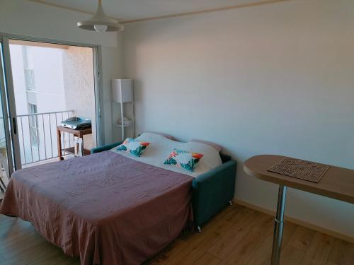 une chambre avec un lit avec une table et un balcon dans l'établissement Six Fours les Plages - Le Brusc - Studio vue mer, climatisé, à Six-Fours-les-Plages