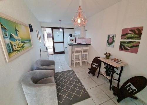a living room with two chairs and a table and a kitchen at Charmoso Flat Funcional No PAPICU Próximo AO SHOPPING RIO MAR in Fortaleza