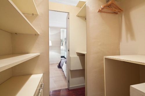 a walk in closet with white shelves and a door at Cathedral Apartment in Barcelona