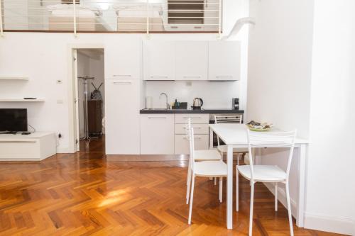 uma cozinha com armários brancos e uma mesa e cadeiras em Loft via morosini centro Varese - IXIHOME em Varese