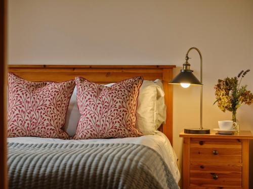 a bed with red and white pillows and a lamp at Linhay, Pattard in Hartland