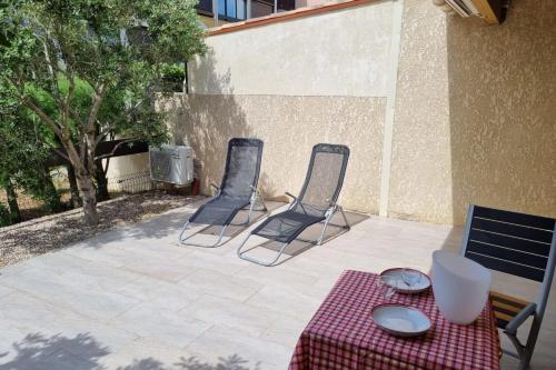 two chairs and a table with a tablecloth on a patio at Cap d'Agde Naturiste Villa Port Vénus in Cap d'Agde