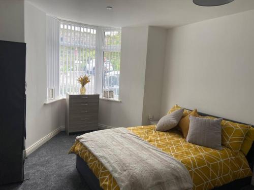 a bedroom with a bed with a yellow blanket and windows at Lovely stylish apartment with breathtaking views. in Llanddulas