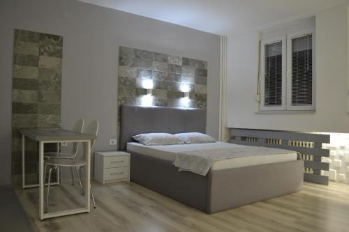 een slaapkamer met een bed, een tafel en een bureau bij Lazarus Studio Apartment in Skopje