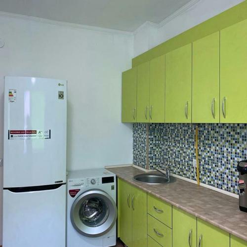 a kitchen with a white refrigerator and a washing machine at Уютная квартира in Taraz